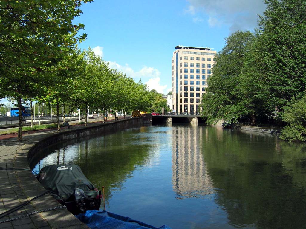 Tall building finds reflection in canal along Mauritskade
