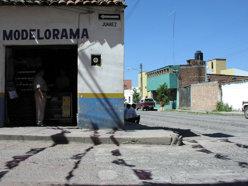Men seek shade near a small shop