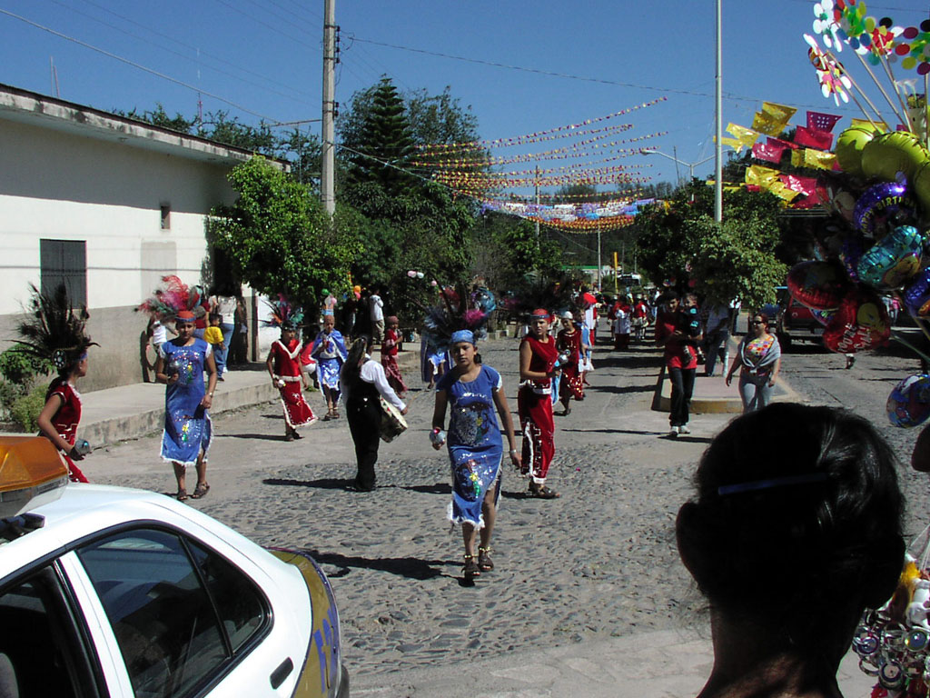 Young girls dressed in traditional dress dance by in a parade